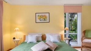 A room with a bed, pillows, a small table with a lamp, a chair, and a window with a view of greenery. - Apartment 'Kneissler' with Mountain View, Private Terrace and Wi-Fi (Oberried)