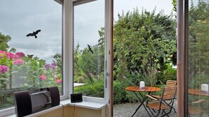 A room with a large window, a radiator, a small table with chairs, and a power outlet. - Apartment 'Kneissler' with Mountain View, Private Terrace and Wi-Fi (Oberried)
