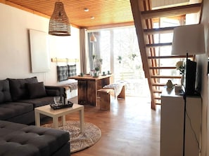 Ein modernes Wohnzimmer mit einer Couch, einem Couchtisch und einem Essbereich mit einem Holztisch und Stühlen.
