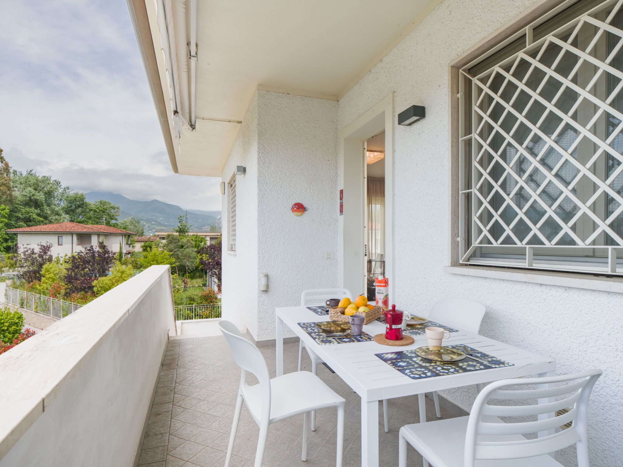 A balcony with a table set for two, chairs, and a view of the surrounding area.