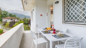 En balkon med et bord dækket til to, stole og udsigt over det omkringliggende område.
