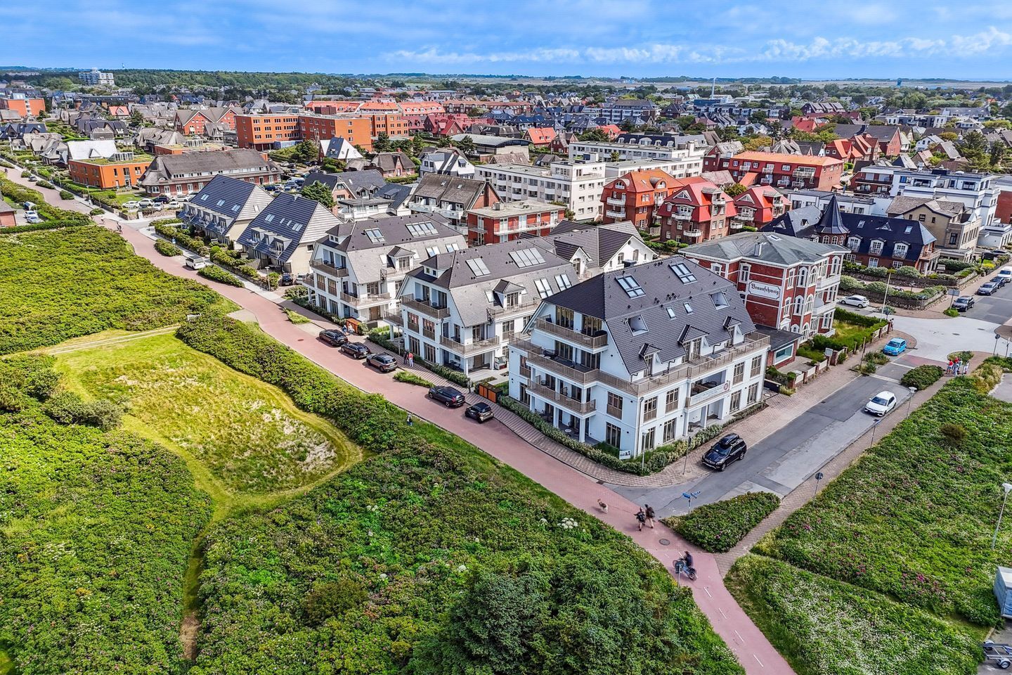 An aerial view of a residential area with modern houses, a well-maintained garden, and a clear road.