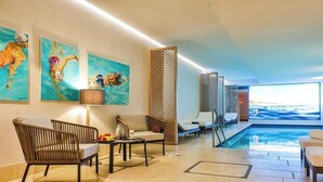 A modern indoor pool area with lounge chairs, a table with fruits, and artwork on the walls. - Dünenloft, Haus Düne Whg. 2 - Dünenlofts (Sylt)