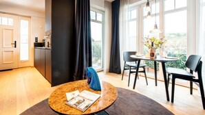 A modern hotel room with a kitchen, dining area, and large windows. - Dünenloft, Haus Düne Whg. 2 - Dünenlofts (Sylt)