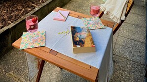 Un patio al aire libre con una mesa lista para dos personas, una silla, una planta en maceta y vistas del paisaje circundante.