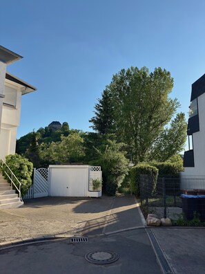 A gated driveway leading to a building with a staircase and a large tree in the background.