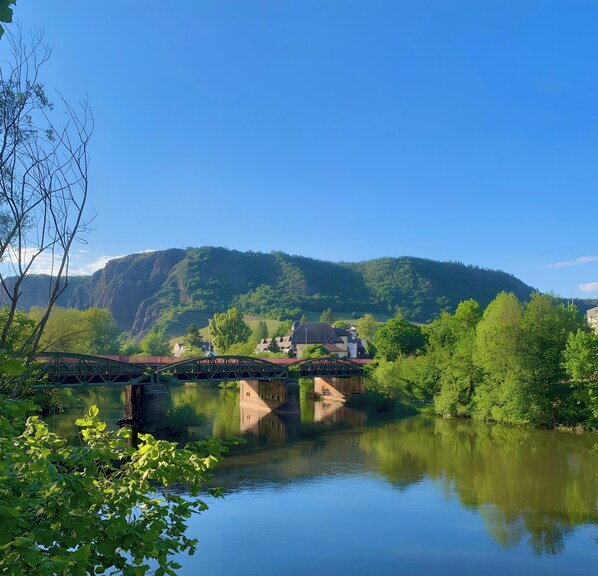 Un río con un puente, una montaña y casas al fondo.