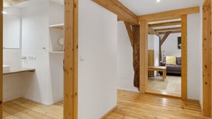 A room with wooden beams, a kitchen area, and a living space with a sofa and a lamp. - Apartment 'Bauernstüble' with Mountain View, Shared Terrace and Wi-Fi (Gutach (Schwarzwaldbahn))