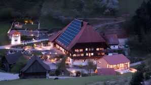 A large house with a sloped roof, a solar panel, and a small adjacent building. - Apartment 'Bauernstüble' with Mountain View, Shared Terrace and Wi-Fi (Gutach (Schwarzwaldbahn))