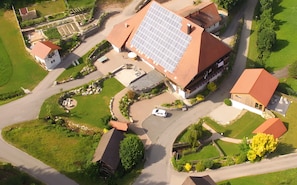 Eine Vogelperspektive eines Wohngebiets mit Häusern, Solaranlagen und einer kurvenreichen Straße.