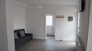 Ein modernes Wohnzimmer mit einem dunkelgrauen Sofa, einem weißen Deckenventilator und einem Holzboden.