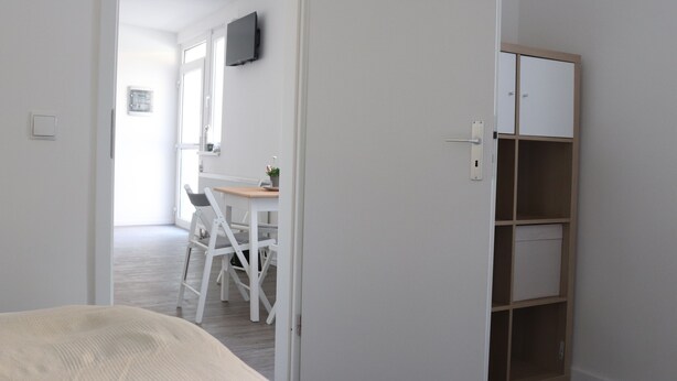 Ein Schlafzimmer mit einem Bett, einem Schreibtisch mit Stuhl, einem Fernseher und einem Kleiderschrank.