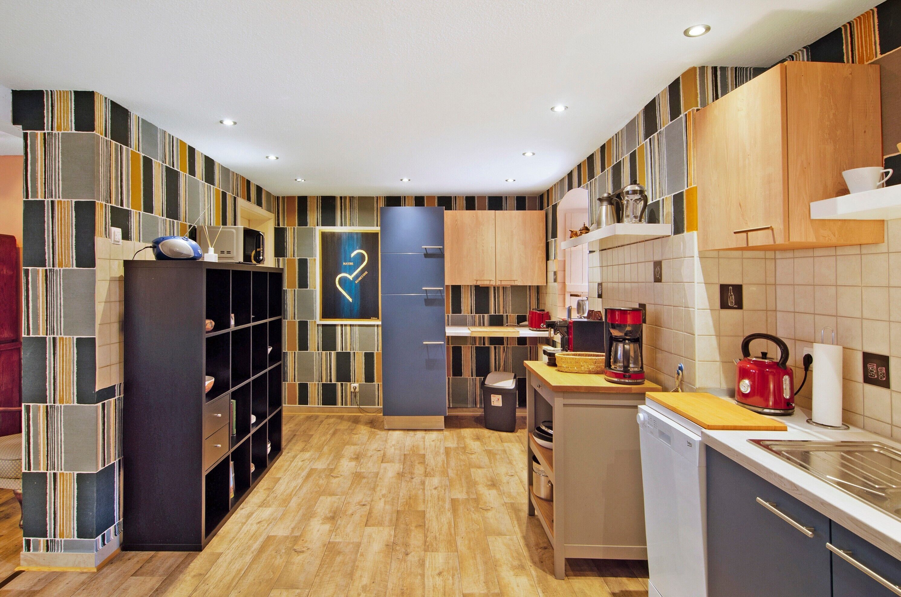 A modern kitchen with a wooden floor, built-in shelves, and a microwave.