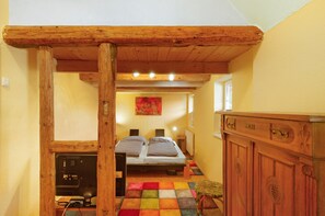 Une pièce étroite avec un plafond en bois, un lit avec deux oreillers, une petite table et un placard.