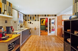 Una cocina moderna con piso de madera, una isla central y vista al área de comedor.