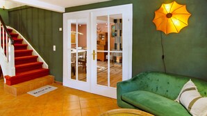 Una escala amb graons vermells, un sofà verd i una porta que dona a una zona de menjador.