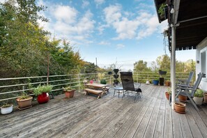 A wooden deck with potted plants, a picnic table, and outdoor furniture.