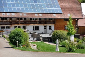 Een gebouw met een dak van zonnepanelen, een stenen trap en een tuin met een bankje.