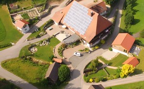 Luchtbeeld van een woongebied met huizen, zonnepanelen en een kronkelende weg.
