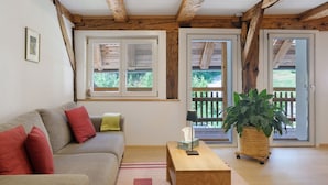 A living room with a sofa, a wooden coffee table, a potted plant, and a sliding glass door leading to an outdoor area. - Apartment 'Mühlenstüble' with Mountain View, Shared Terrace and Wi-Fi (Gutach (Schwarzwaldbahn))