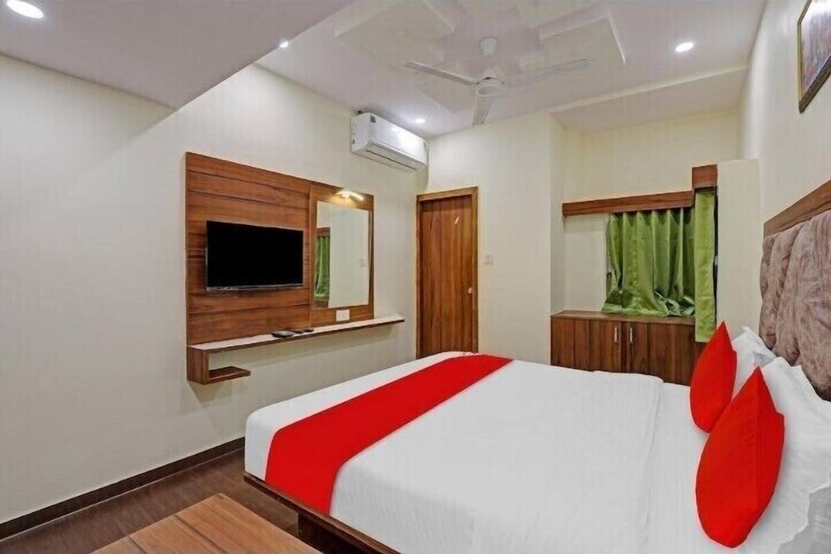 Ein Hotelzimmer mit Bett, Wandfernseher, Kleiderschrank und Deckenventilator.