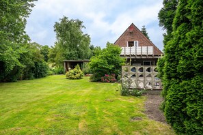 Un jardin avec une maison en briques, une construction en pierre et une végétation luxuriante.