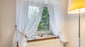 A room with a window, a radiator, a lamp, and a bird figurine on the windowsill. - Apartment 'Ella Walter, Kiek Ut' with Private Terrace, Shared Garden and Wi-Fi (Nordstrand)