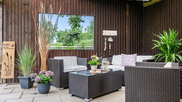 An outdoor seating area with wicker furniture, potted plants, and a view of the outdoors. - Apartment 'Ella Walter, Kiek Ut' with Private Terrace, Shared Garden and Wi-Fi (Nordstrand)