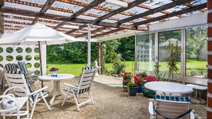 A covered patio with outdoor furniture, a pergola, and a view of a garden. - Apartment 'Obendrot' with Shared Terrace, Shared Garden and Wi-Fi (Nordstrand)