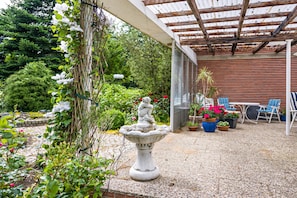 A patio with a stone fountain, potted plants, and outdoor furniture.
