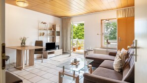 Un soggiorno moderno con un tavolino in vetro, un divano, una TV e un'area pranzo con tavolo e sedie.