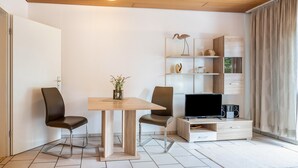 Un soggiorno moderno con un tavolo in legno, due sedie, una TV e una libreria.