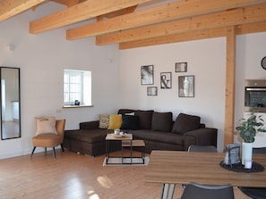 Una sala de estar moderna con techo de madera, un sofá, una mesa de centro y una mesa de comedor.