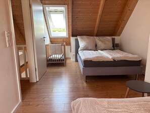 Une chambre avec un plafond en bois, un lit superposé, une fenêtre et une table de chevet.