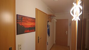 Een gang met houten deuren, een zonsondergangschilderij en een plafondlamp.