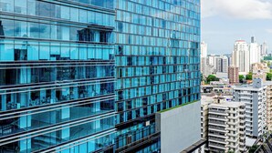 Ein modernes Hochhaus mit spiegelnden Glasfenstern und einer Stadtansicht im Hintergrund.