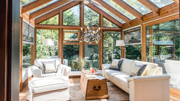 A spacious room with a high ceiling and large windows, furnished with a white sofa and two white armchairs, and a wooden chest of drawers. - Holiday Home 'Am Meer' with Sea View, Private Terrace and Wi-Fi (Langballig)