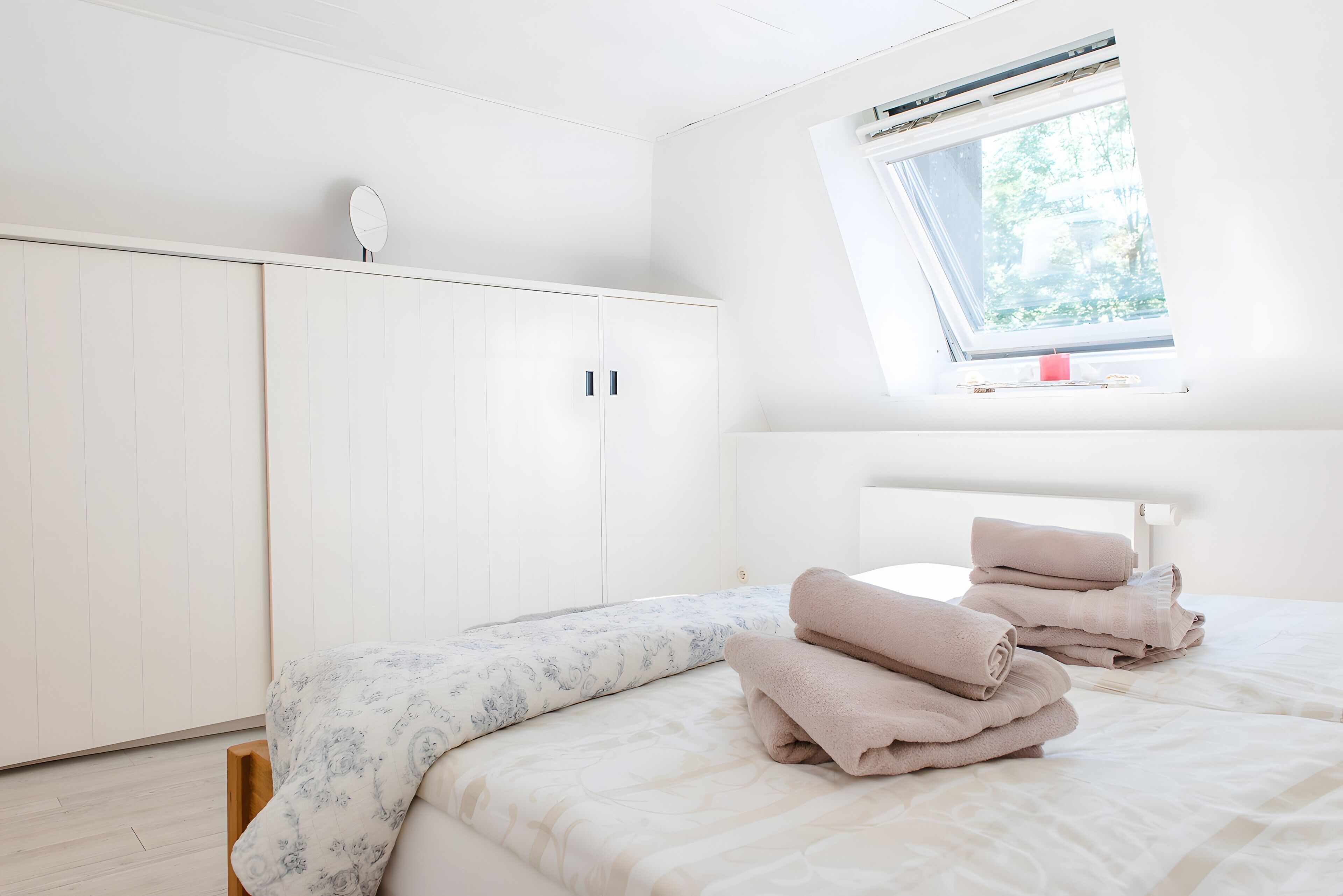 A bedroom with a bed, a window, and a wardrobe.