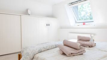 A bedroom with a bed, a window, and a wardrobe.