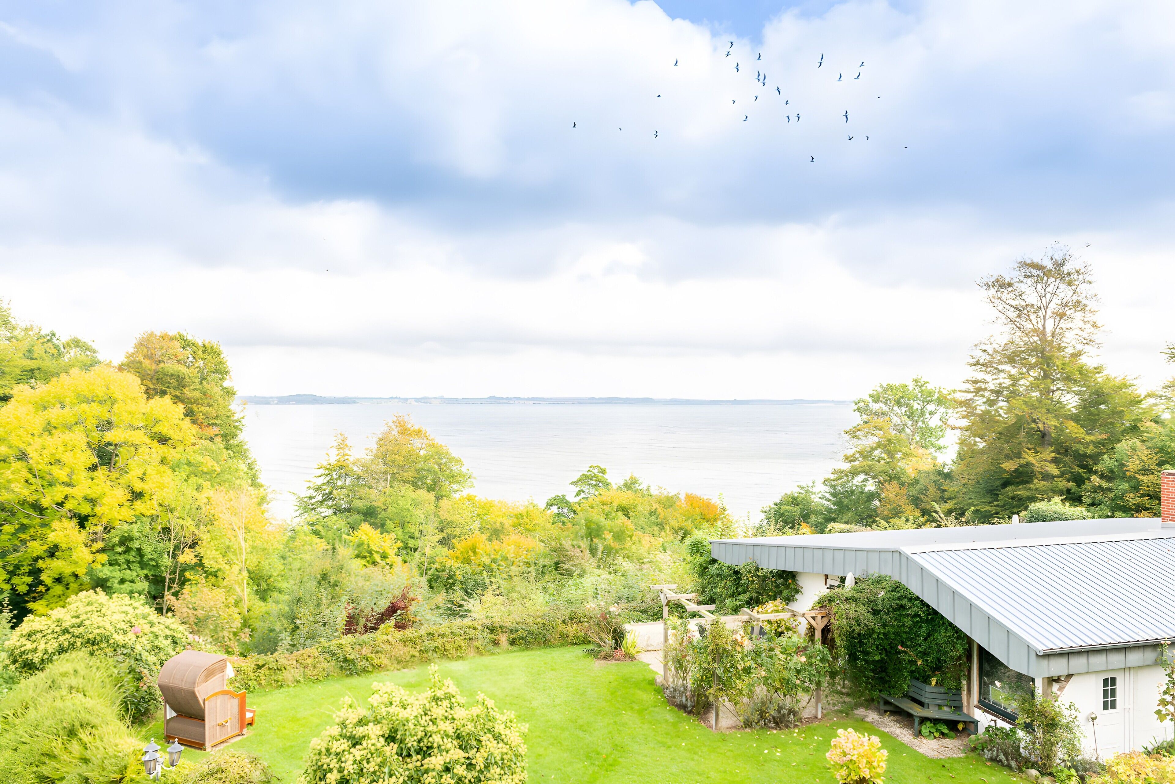 Une maison avec vue sur l’eau, entourée de verdure.