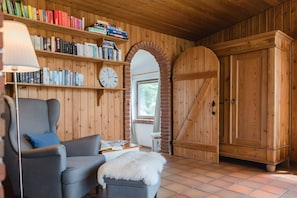 A cozy room with a wooden interior, a bookshelf, a clock, a chair, and a wardrobe. - Holiday Home 'Hanghaus Am Meer' with Sea View, Private Terrace and Wi-Fi (Langballig)