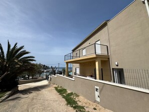 Un bâtiment moderne doté d’un balcon, d’une petite piscine et offrant une vue dégagée sur la mer.