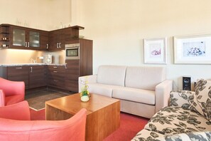 A modern living room with a sofa, a coffee table, and a kitchen area with cabinets and appliances. - Ferienwohnungen im Seepark Sellin (Sellin)