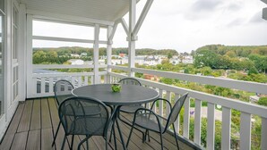 Un espace extérieur abrité, doté d’une table et de chaises, qui offre une vue sur un quartier résidentiel.