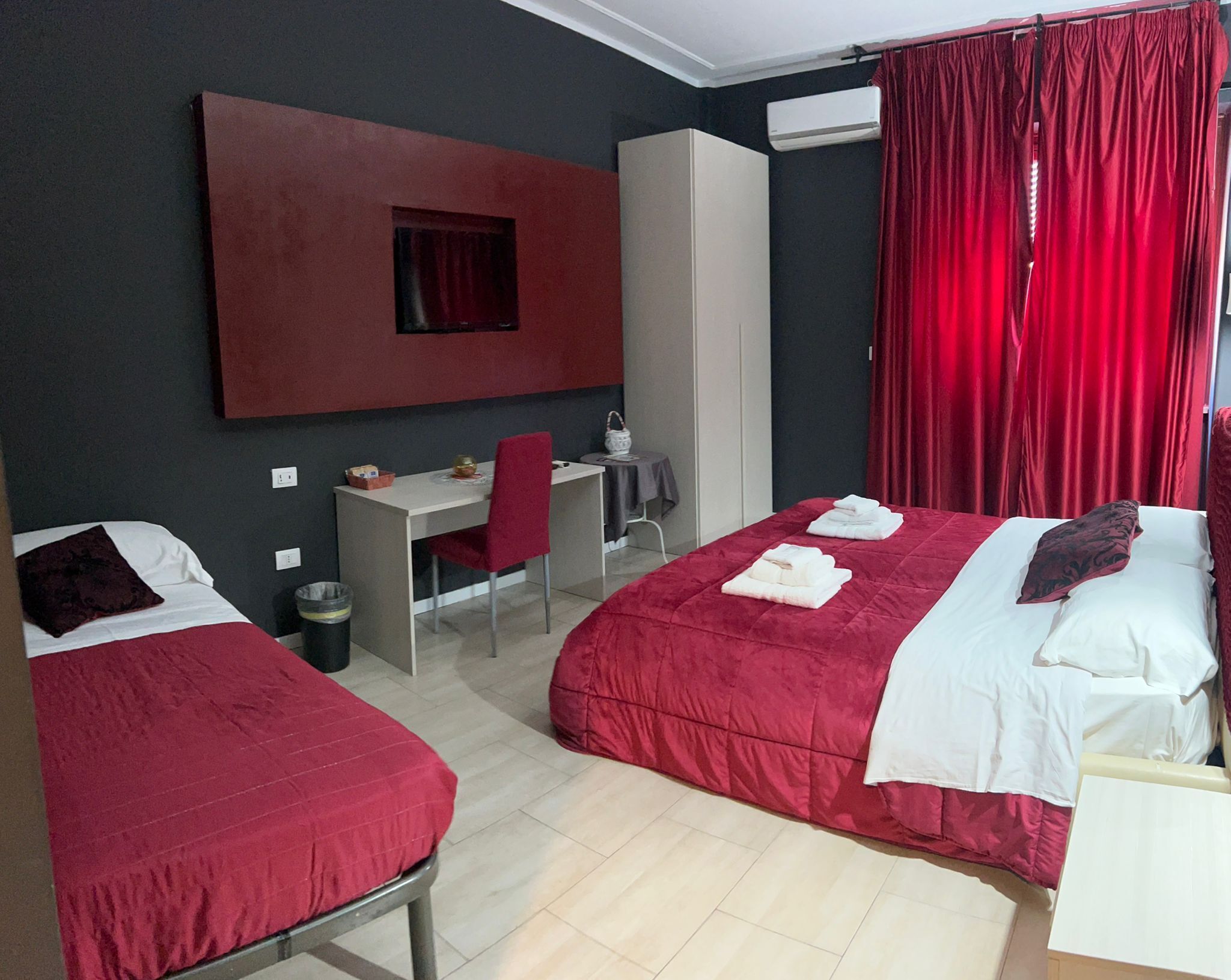 Ein Hotelzimmer mit zwei Betten, einem Schreibtisch, einem Stuhl und einem Kleiderschrank.