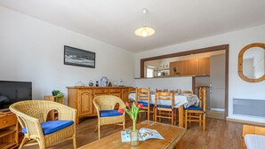 A cozy living room with wicker furniture, a wooden coffee table, and a dining area with wooden chairs and a table. - Ty Bara by Interhome (Carnac)