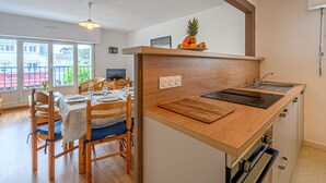 A modern kitchen with wooden countertops, a built-in oven, and a dining area with wooden chairs and a table. - Ty Bara by Interhome (Carnac)