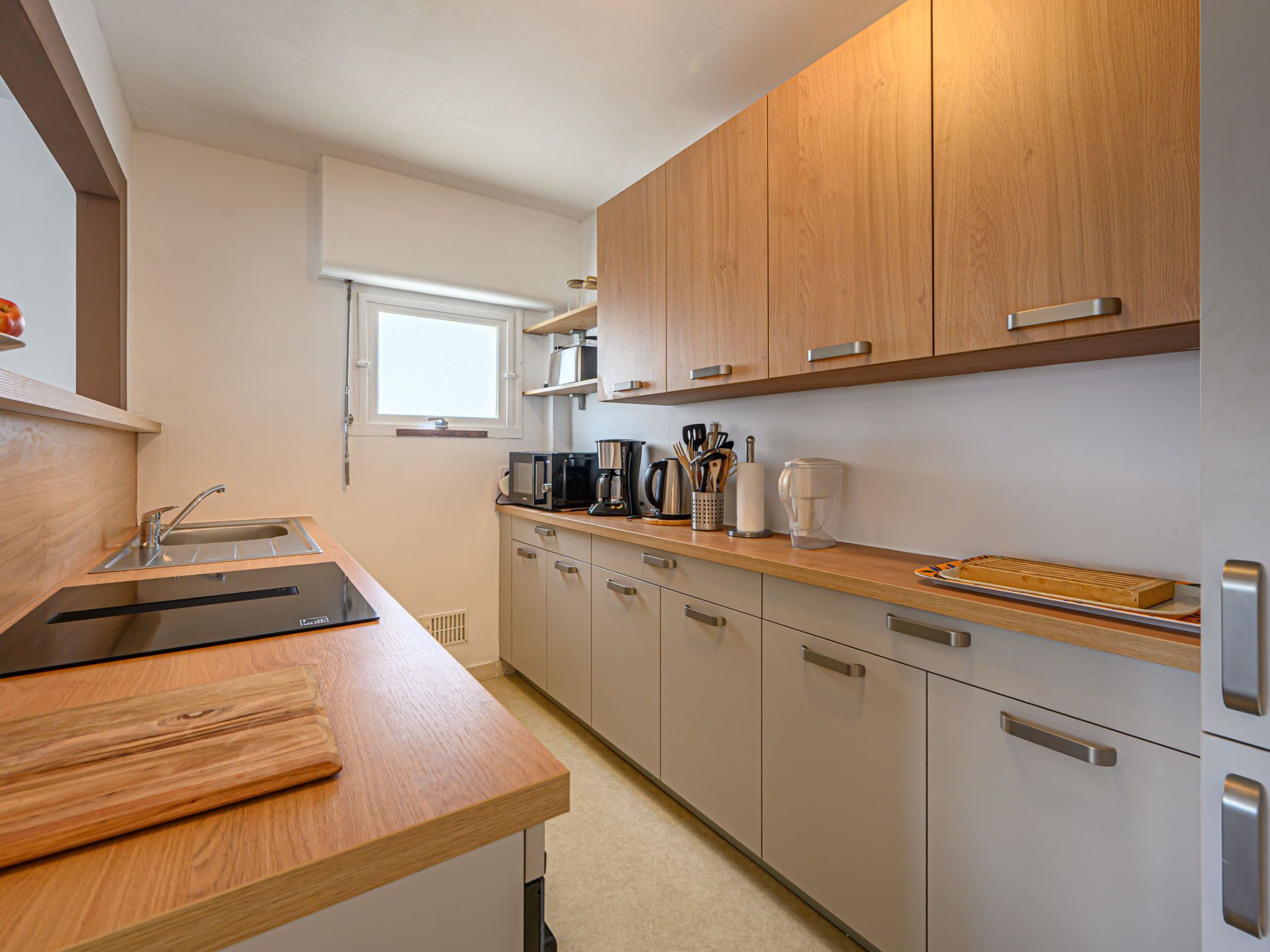 A modern kitchen with wooden cabinets, a stainless steel sink, and a built-in oven.