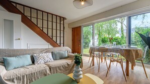 A modern living room with a sofa, a dining table, and a staircase.