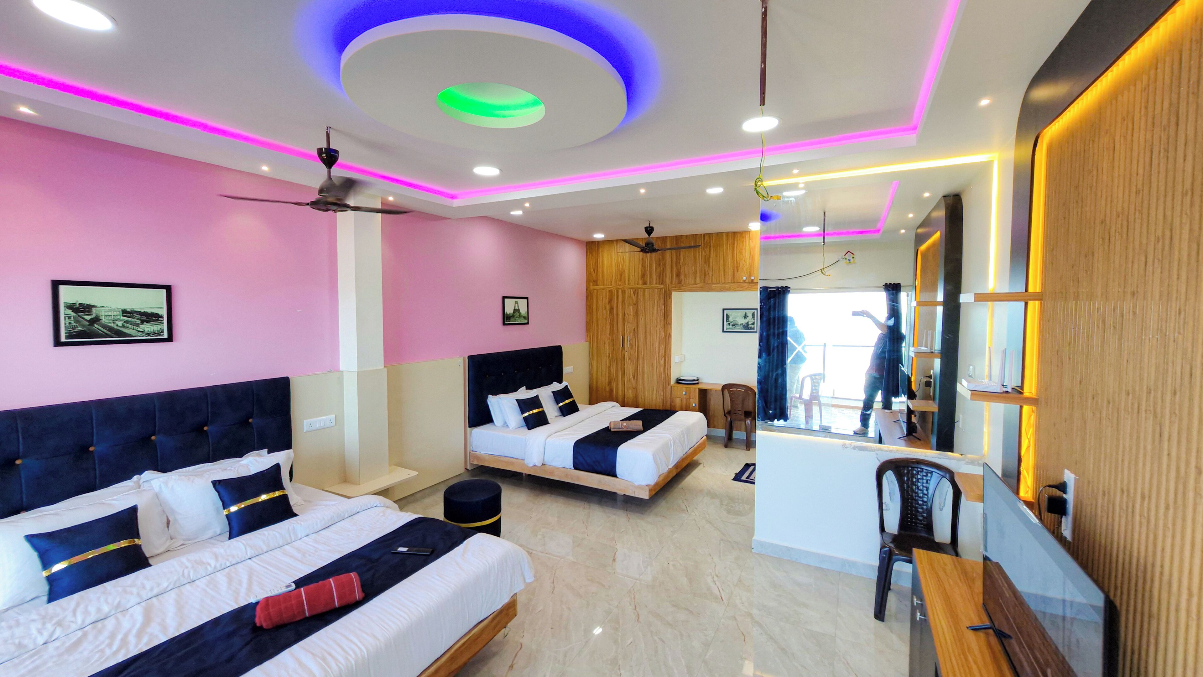 A modern hotel room with two beds, a desk, a chair, and a large mirror.
